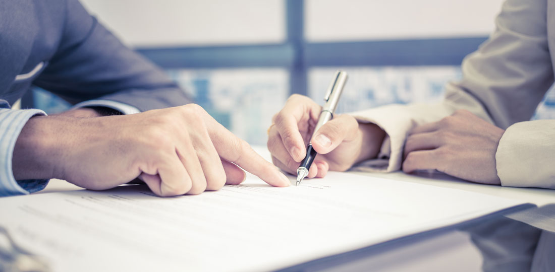 A consultant showing a businessman where his signature is required on a contract.
