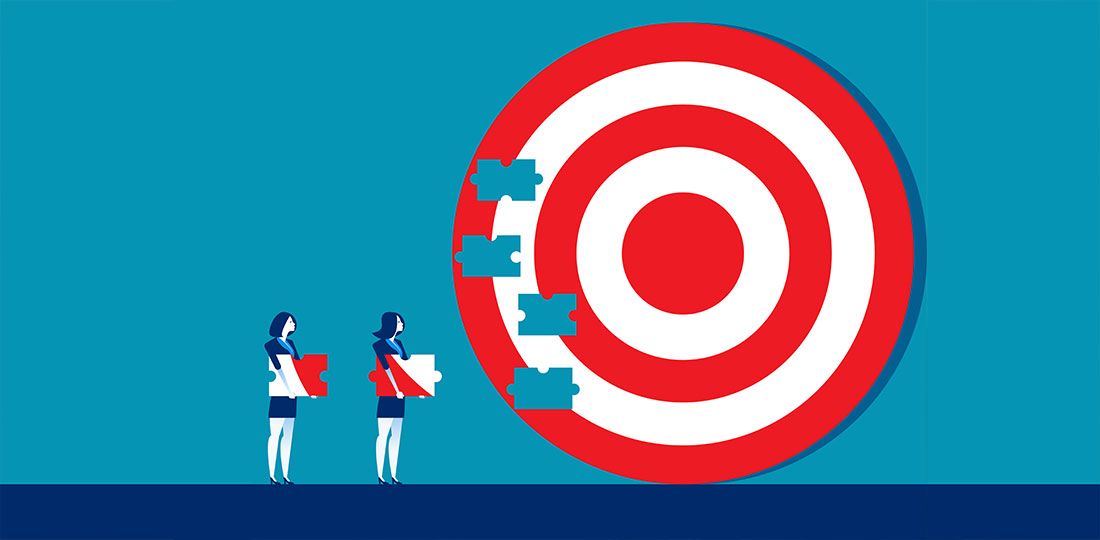 Two businesswomen carrying puzzle pieces towards a large jigsaw of a bullseye target. Illustration.